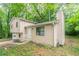 View of house with beige siding, a chimney, and mature trees in backyard at 5218 Tina Ct, Stone Mountain, GA 30083