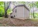 Two-story home exterior with light siding surrounded by lush greenery and mature trees at 5218 Tina Ct, Stone Mountain, GA 30083