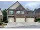 Townhome exterior with a three-car garage, brick facade, and covered entrance on a cloudy day at 805 Pleasant Hill Nw Rd # 53, Lilburn, GA 30047