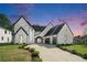 Beautiful two-story home featuring a manicured lawn and striking black and white design at dusk at 115 Thome Dr, Alpharetta, GA 30022