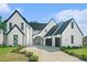 Stunning exterior of a modern home with black trim, arched doorway, and a concrete driveway leading to a two-car garage at 115 Thome Dr, Alpharetta, GA 30022