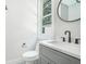 Modern powder room with a sleek vanity, round mirror, and natural light from the window at 115 Thome Dr, Alpharetta, GA 30022