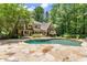 Beautiful backyard featuring a pool, stone patio, lush landscaping, and mature trees at 4161 Thunderbird Se Dr, Marietta, GA 30067