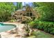 Tranquil backyard with an in-ground pool, stone patio, lush landscaping, and mature trees at 4161 Thunderbird Se Dr, Marietta, GA 30067