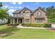 Beautiful stone and brick home with a manicured lawn, established bushes, and three-car garage at 6625 Baywood Run, Cumming, GA 30041