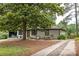 Beautiful single-story home featuring mature trees, a brick facade, and a cozy front sitting area at 1195 Russell Dr, Decatur, GA 30030