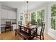 Bright dining area with a wooden table, bench, and large windows offering a view of the outdoor greenery at 1860 Hill Chase, Alpharetta, GA 30022