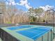 A full view of blue and green tennis courts surrounded by a black fence and trees in the background at 1860 Hill Chase, Alpharetta, GA 30022
