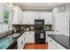 Charming kitchen with white cabinetry, black appliances, and granite countertops at 927 Ivey Chase Pl, Dacula, GA 30019