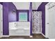 Bright bathroom with white tub and shower, complimented by unique purple wall color and wood flooring at 5115 Estonian Dr, Fairburn, GA 30213