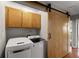 Laundry room with a sliding barn door, washer, dryer, and overhead storage at 215 Truehedge Trce, Roswell, GA 30076