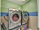 Well-lit laundry room with stainless steel washer and dryer, and a shelving unit at 2612 Back Creek Chase, Dacula, GA 30019