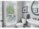Stylish powder room with a pedestal sink, round mirror and window with plantation shutters at 4588 Pine Se St, Smyrna, GA 30080