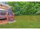 Large backyard with green grass, a wooden deck with a canopy, and mature trees at 3780 Summit Gate Dr, Suwanee, GA 30024