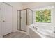 Bright bathroom featuring a shower, large tub by a window with natural light and a white door at 3780 Summit Gate Dr, Suwanee, GA 30024