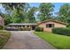 Ranch style home featuring a long driveway, brick facade, manicured shrubs, and mature trees at 3946 Flakes Mill Rd, Decatur, GA 30034