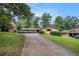 Ranch style home featuring a long driveway, brick facade, manicured shrubs, and mature trees at 3946 Flakes Mill Rd, Decatur, GA 30034