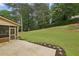 Large grassy backyard with a concrete patio, a screened-in porch, and landscaping along the border at 5545 Durrett Dr, Atlanta, GA 30338