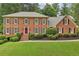 Beautiful two-story brick home with dark shutters, manicured shrubs, and a green lawn at 5545 Durrett Dr, Atlanta, GA 30338