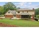 View of the home's rear elevation with a brick and tan siding exterior, a screened-in porch, and a large yard at 5545 Durrett Dr, Atlanta, GA 30338