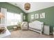 Cozy Bedroom featuring a white crib, an accent chair, and a large window at 327 Nobleman Way, Canton, GA 30114