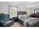 A sunlit bedroom offers a relaxing retreat with a cozy armchair, patterned pillows, and bedside tables at 2127 Apple Orchard Way, Austell, GA 30168