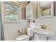 This features a white toilet and sink, a window for natural light, and white tiled walls at 118 Greenwood St, Fairburn, GA 30213