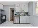 Bright kitchen with white cabinets and appliances, adjacent to another living space at 118 Greenwood St, Fairburn, GA 30213