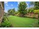 Lush backyard featuring manicured landscaping, a gentle slope with garden beds, and an inviting patio area at 2115 Creekstone Point Dr, Cumming, GA 30041