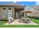 Outdoor patio has an umbrella, table with chairs, and comfortable sofa in a grassy backyard at 2115 Creekstone Point Dr, Cumming, GA 30041