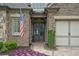 Inviting home entrance with stone and brick accents, a well-manicured garden, and a decorative American flag at 2115 Creekstone Point Dr, Cumming, GA 30041