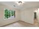 This bedroom has neutral walls, beige carpeting, a closet with folding louvered doors, and a large window at 3564 Liberty Ln, Marietta, GA 30062