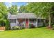 Charming home featuring a well-manicured lawn, cozy front porch, and vibrant red front door at 5761 E Emerald Oaks Ln, Acworth, GA 30102