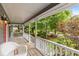 A sunlit front porch features wicker furniture and a view of the lush, green yard and trees at 5761 E Emerald Oaks Ln, Acworth, GA 30102