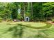 Backyard featuring putting green, bench, mature trees and lush landscaping at 302 Chinquapin Sw Dr, Marietta, GA 30064
