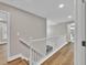 Well-lit hallway with hardwood floors and white railing leading to other areas of the home at 1547 Trilogy Park, Hoschton, GA 30548