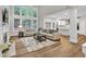 Open-concept living room with hardwood floors, a fireplace, and large windows offering plenty of natural light at 1547 Trilogy Park, Hoschton, GA 30548