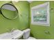 Green powder room features window with blind and round mirror at 2644 Hickory Valley Dr, Snellville, GA 30078
