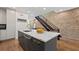 Kitchen island with sink, marble countertop, stainless steel appliances and dark cabinets, next to a brick accent wall and stairs at 1308 Fernwood Ne Cir, Atlanta, GA 30319