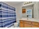 Bright bathroom featuring a shower with a blue and white striped curtain and a light wood vanity at 1942 Westover Nw Ln, Kennesaw, GA 30152