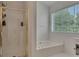 Well-lit bathroom features a shower with glass door, soaking tub and a large window with blinds at 1942 Westover Nw Ln, Kennesaw, GA 30152