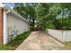 Driveway with a white picket fence and a mix of lush green trees, bushes, and tall grass at 2881 Bridle Creek Sw Dr, Conyers, GA 30094
