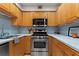 Compact kitchen with wood cabinets, stainless steel appliances, and light blue backsplash at 2479 Peachtree Ne Rd # 305, Atlanta, GA 30305