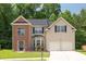 Charming two-story home featuring a manicured lawn, brick accents, and a two-car garage at 4608 Treasure Ct, Forest Park, GA 30297