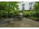 Stone patio with elegant outdoor dining set, surrounded by mature trees and manicured landscaping at 2 W Muscogee Nw Ave, Atlanta, GA 30305
