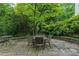 An outdoor dining set on a stone patio surrounded by lush landscaping and mature trees at 2 W Muscogee Nw Ave, Atlanta, GA 30305