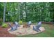 Cozy backyard fire pit with six Adirondack chairs surrounded by lush greenery at 123 Mill Ln, Dallas, GA 30157