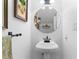 Stylish powder room featuring a round mirror and a sleek pedestal sink at 2779 Bentley Se Pl, Marietta, GA 30067