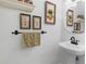 Elegant powder room with a pedestal sink, framed art, and modern black hardware at 2779 Bentley Se Pl, Marietta, GA 30067