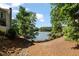 Backyard leading to the lake featuring a sandy beach area, mature trees, and direct access to the water at 7815 Bamby Rd, Cumming, GA 30041